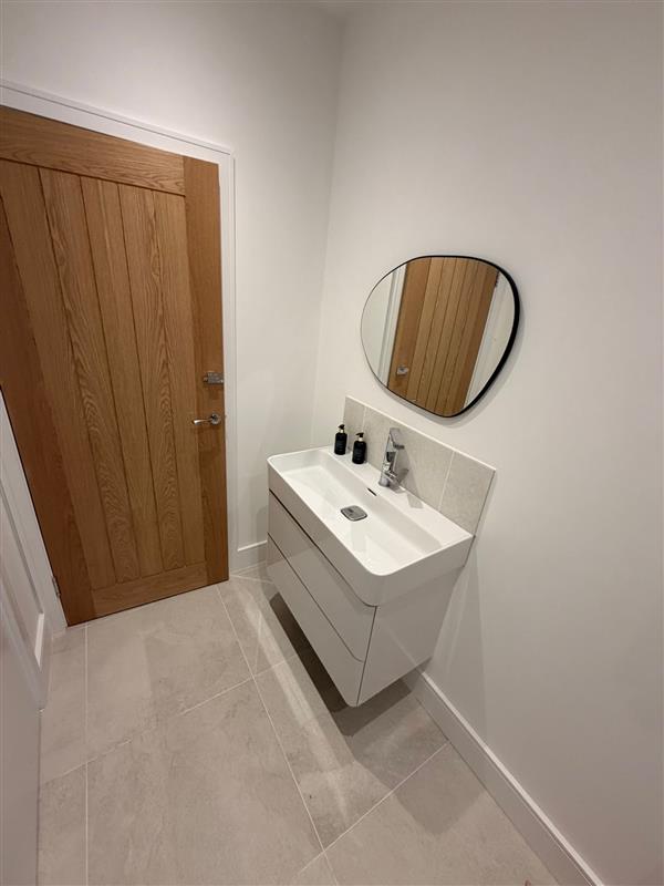 Cloakroom with wall hung vanity unit, round mirror and oak door