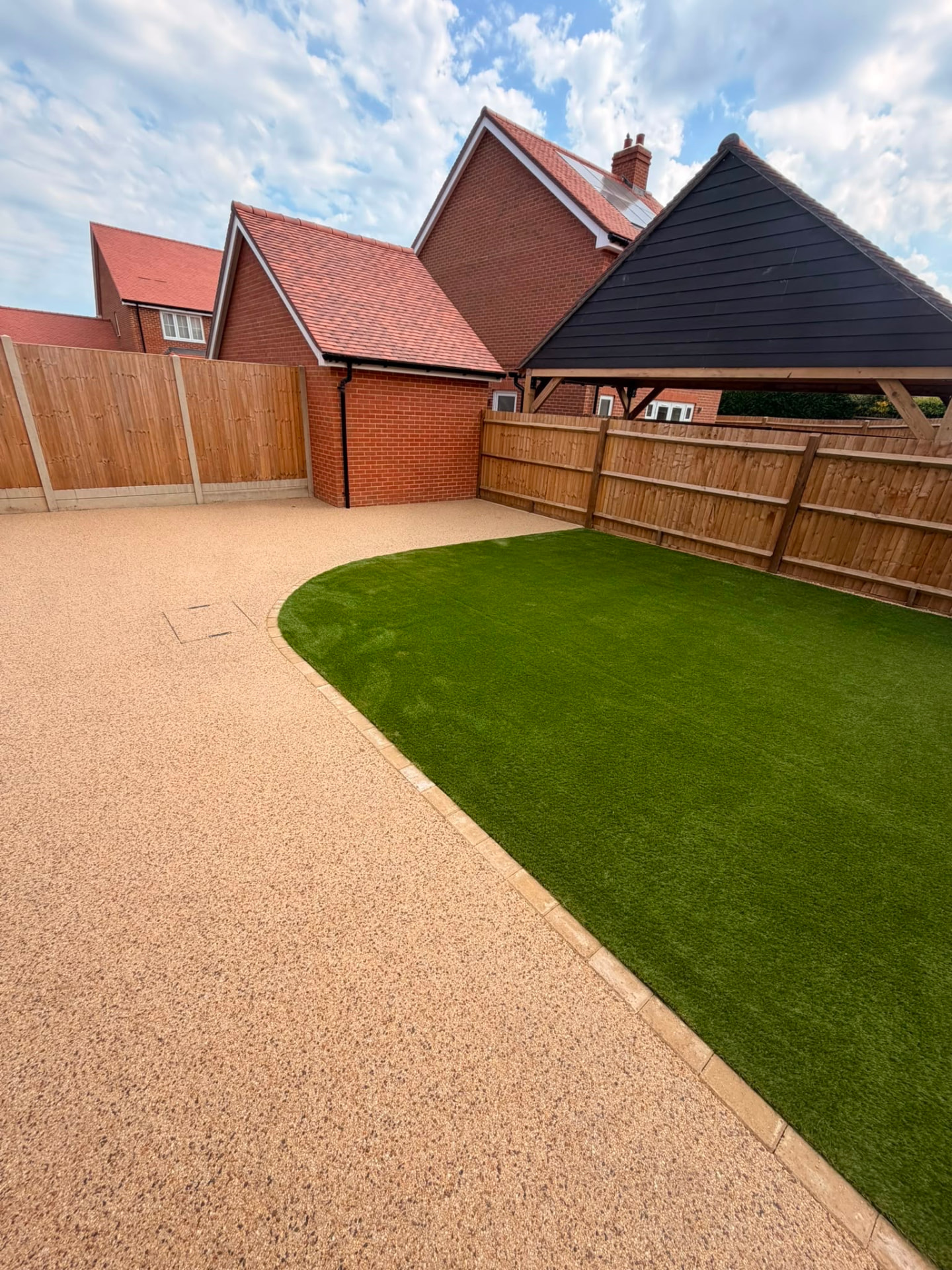 Curved artificial lawn with block edging set into a resin bound patio