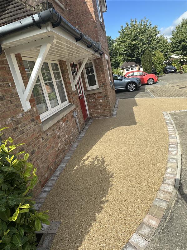 Resin bound driveway and pathway with setts edging running alongside a red brick home