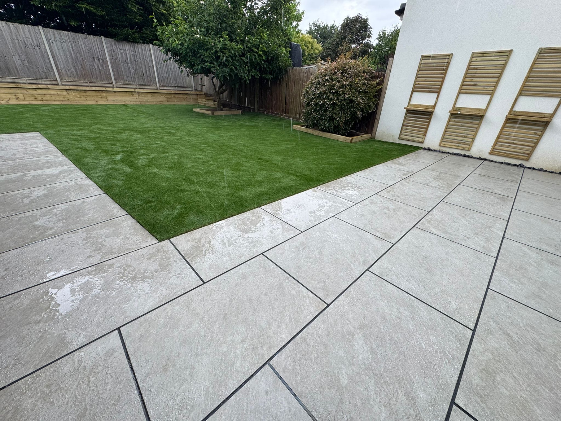Grey porcelain patio with artificial lawn and timber raised beds built by Hodges Building & Landscaping