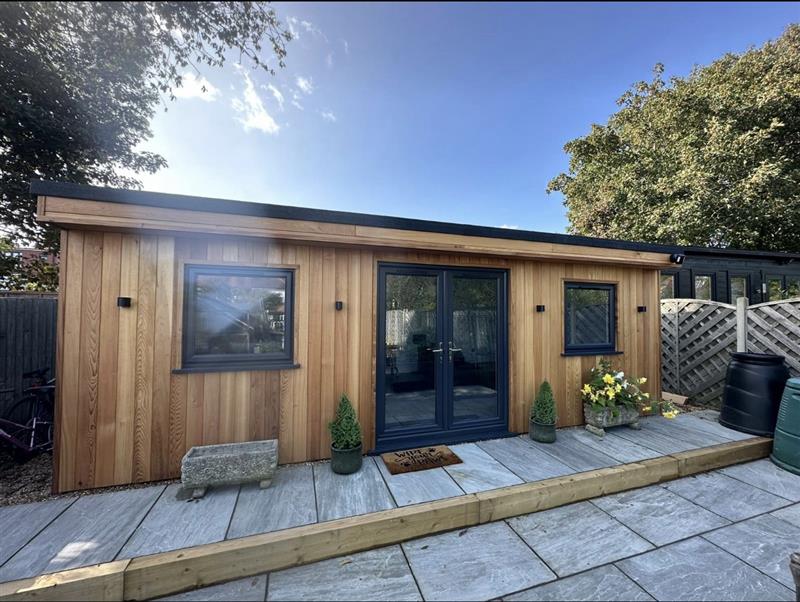 Large cedar garden room with navy French doors and windows on a paved patio