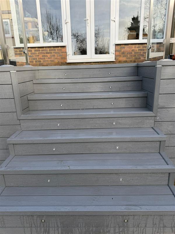 Grey composite decking steps with recessed stair lighting and matching side panels